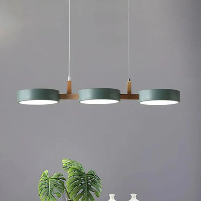 Modern green three-light pendant lamp with natural wood accents, featuring a sleek linear design suitable for dining room or kitchen lighting.
