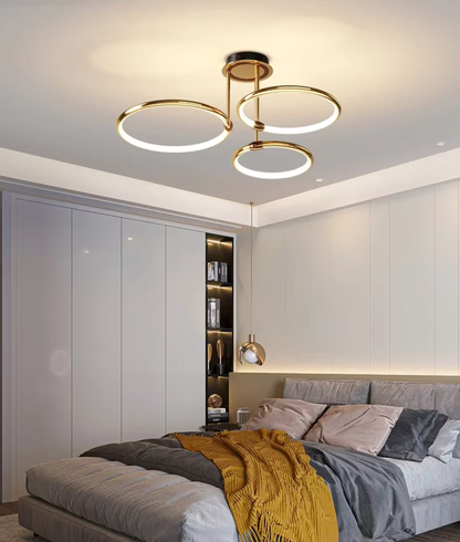 Gold three-ring LED ceiling light in a bedroom