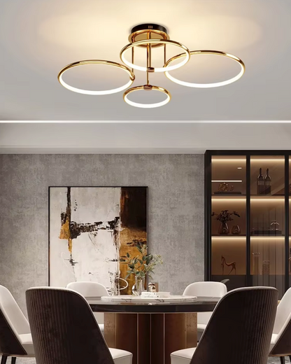 Gold four-ring LED ceiling light above a dining table