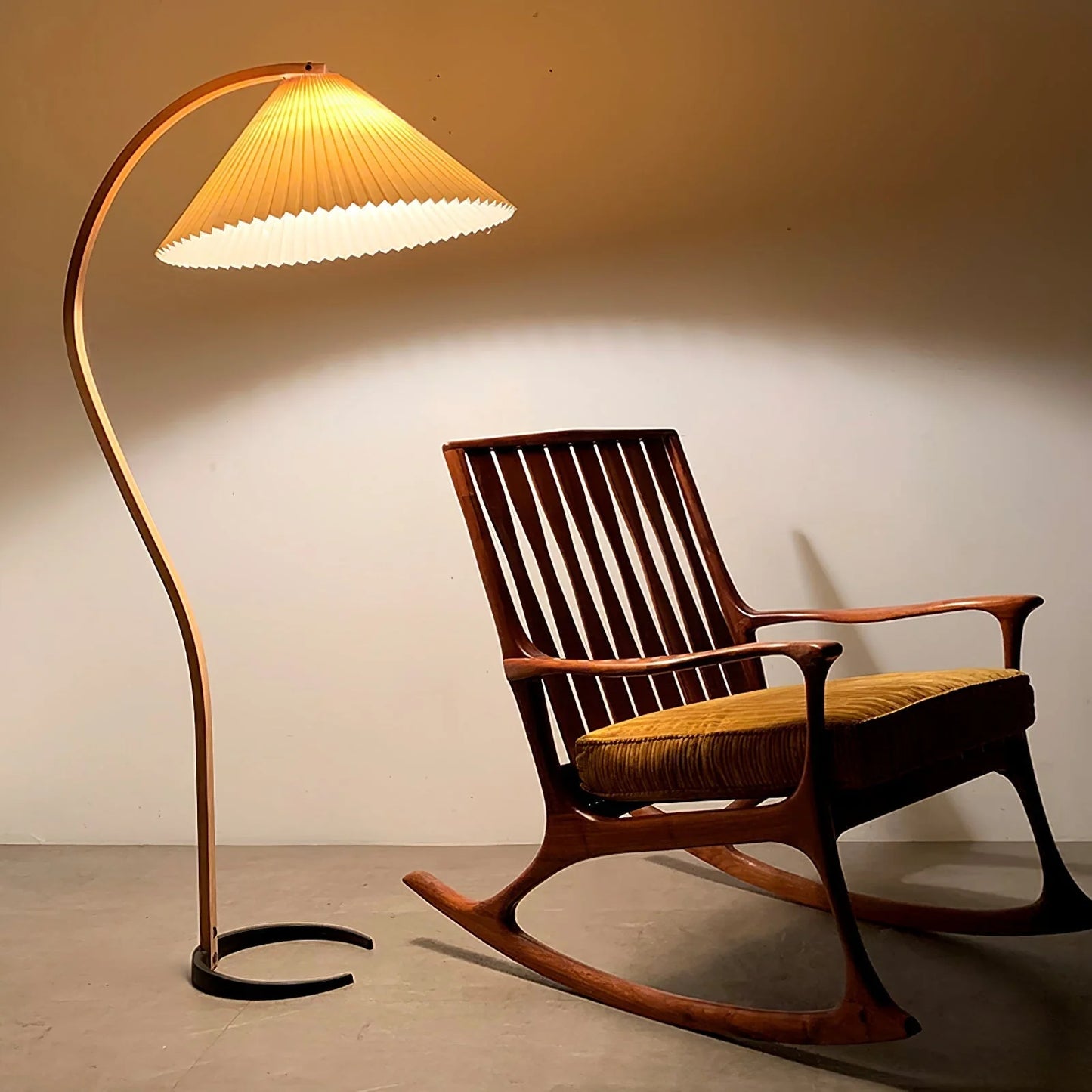 Nordic beech wood floor lamp with a pleated shade casting a warm glow next to a wooden rocking chair in a modern living room setting.