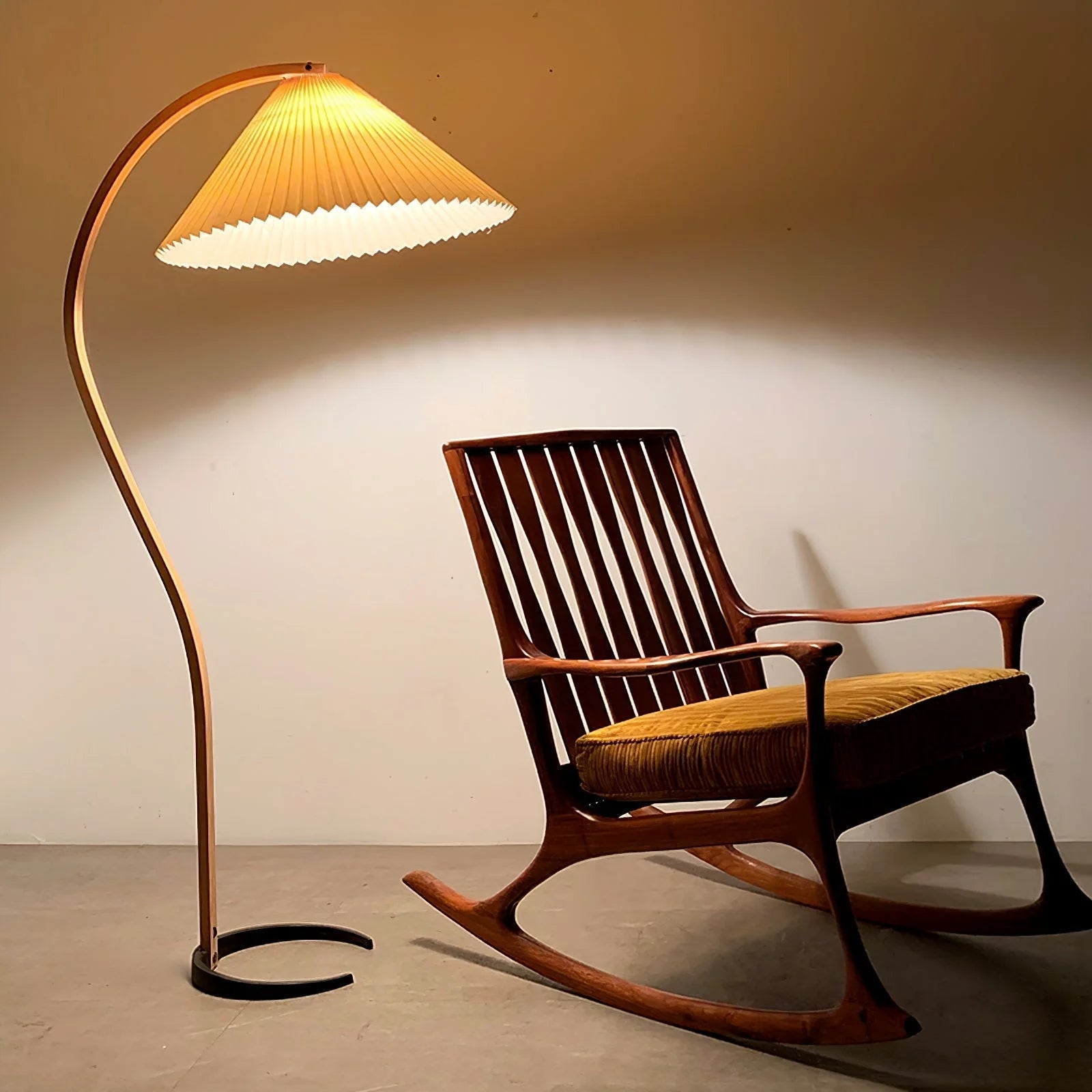 Nordic beech wood floor lamp with a pleated shade casting a warm glow next to a wooden rocking chair in a modern living room setting.