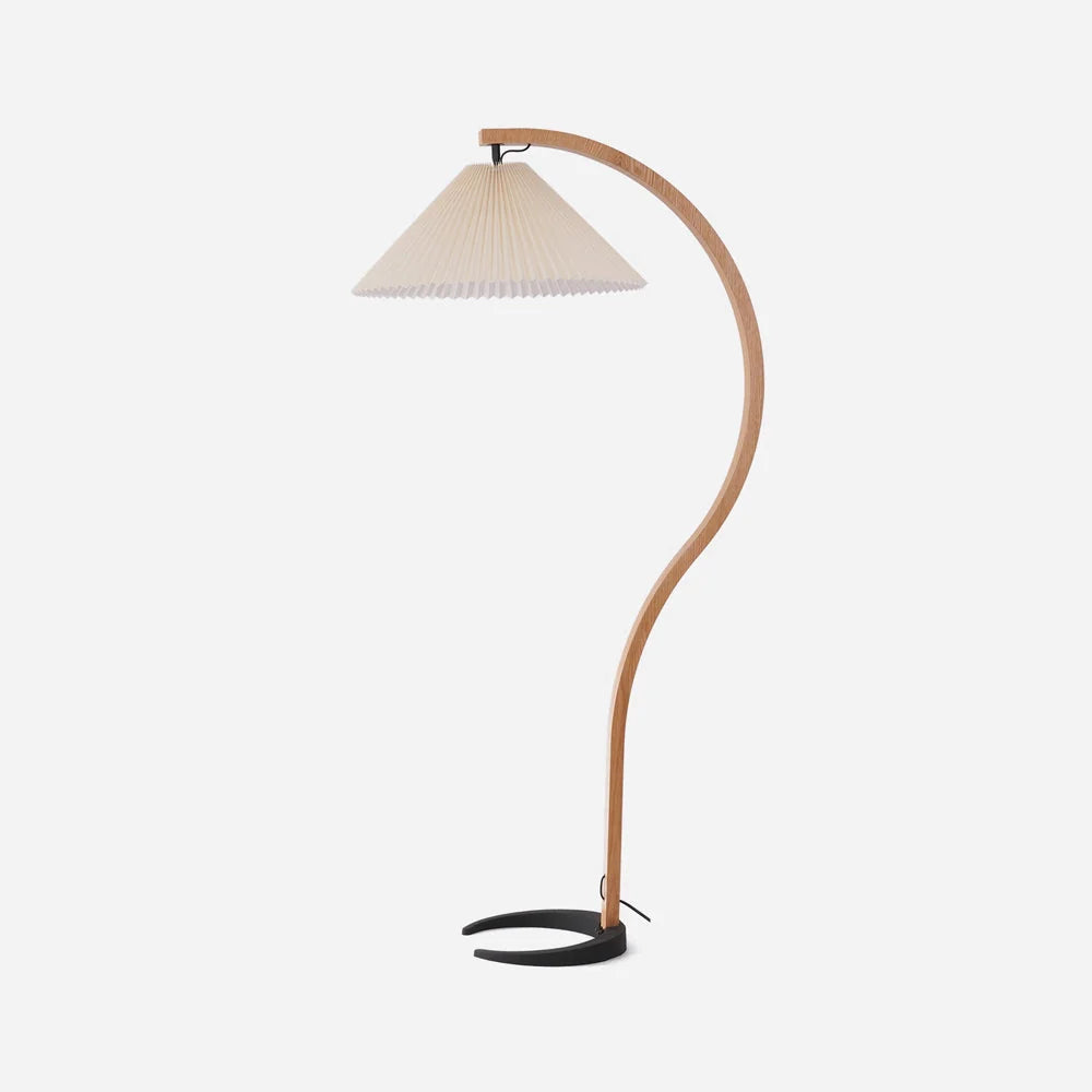 Nordic style floor lamp featuring a curved beech wood stand, a cream-coloured pleated shade, and a sturdy black crescent-shaped base on a white background.