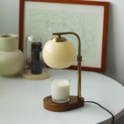 Beige glass candle warmer with a gold frame and wood base
