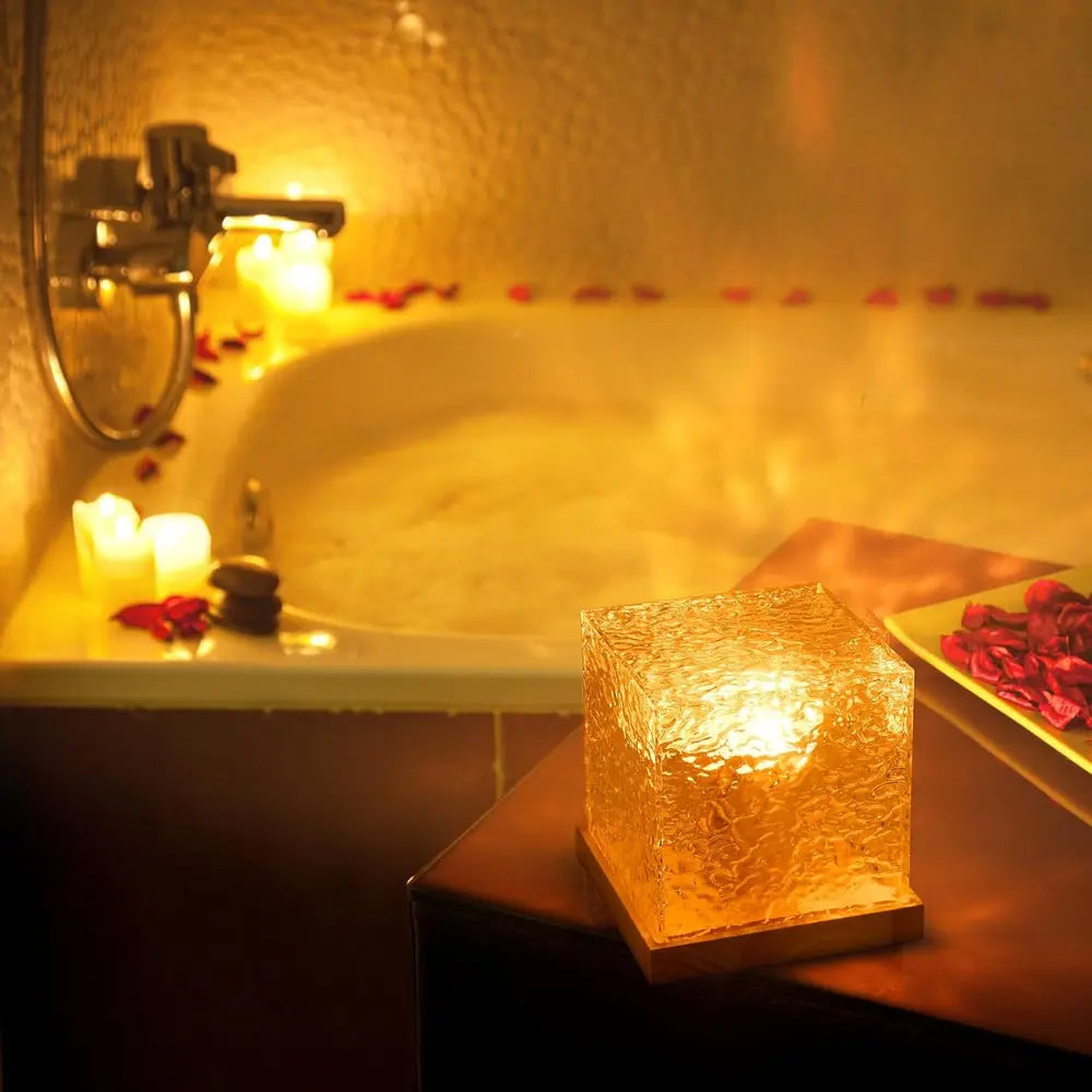 Cube mood lamp casting warm patterned light beside a bed
