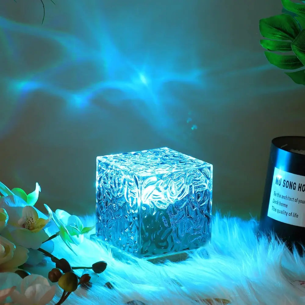Cube lamp casting blue light beside flowers