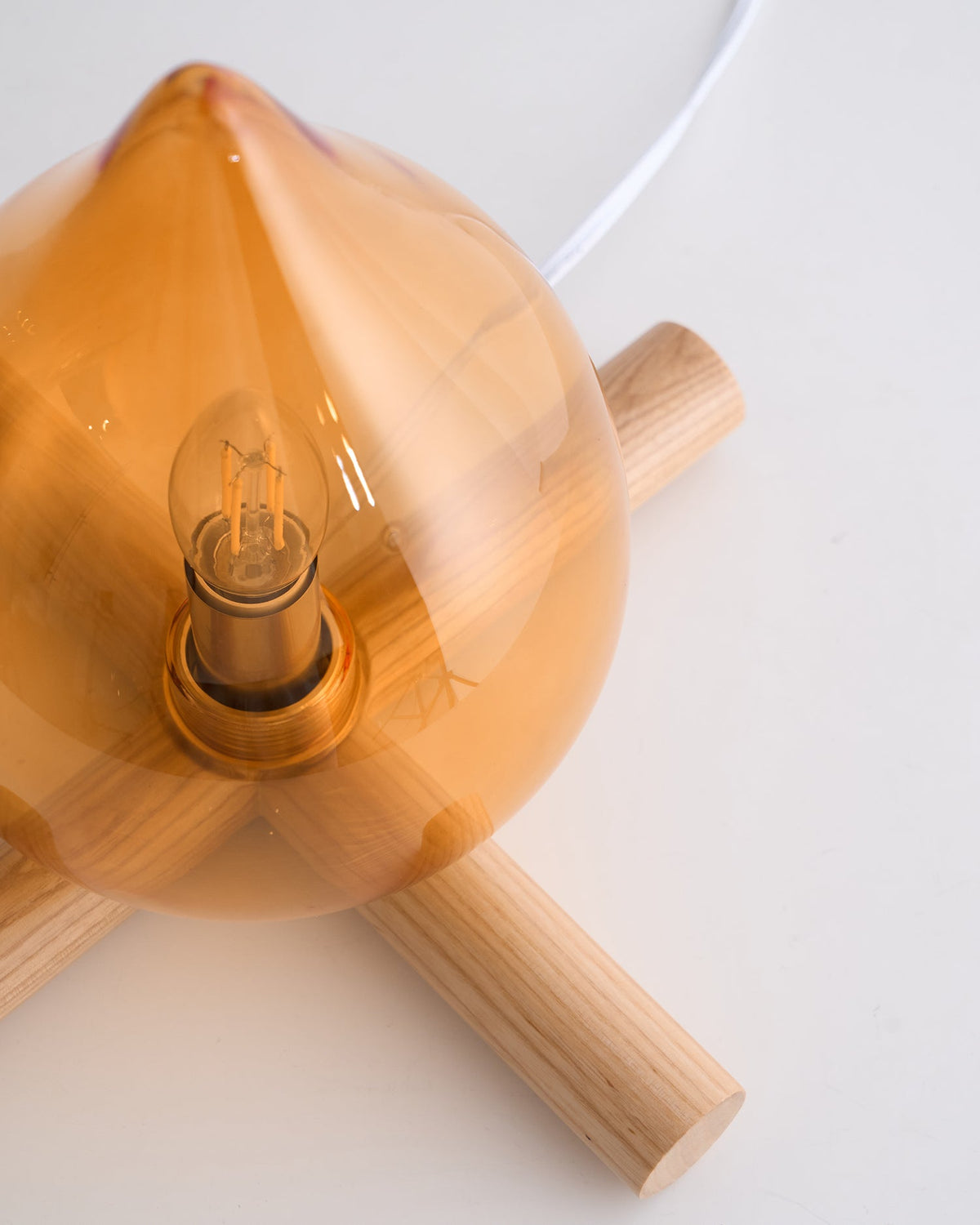 Top view of flame-shaped orange glass shade and wooden cross base
