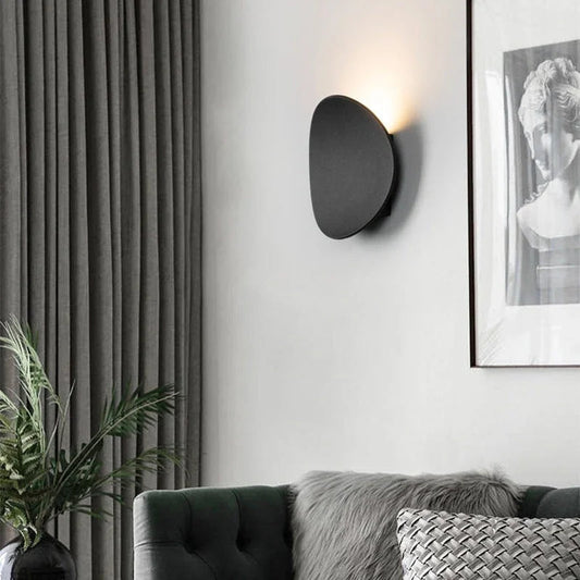 Black pebble wall light above a sofa