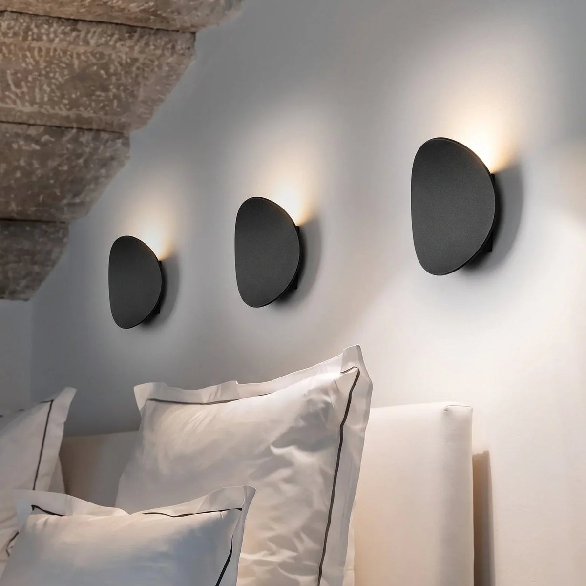 Three black pebble lights above a bed