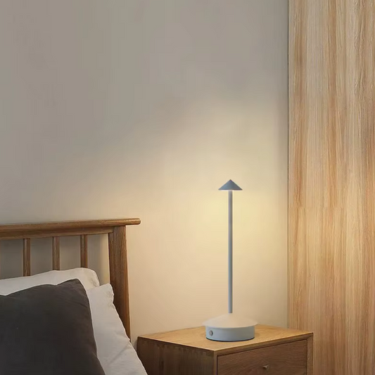 White rechargeable cone table lamp beside a bed