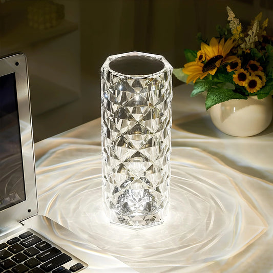 Clear faceted cylinder lamp casting patterned light beside a laptop