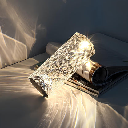 Faceted acrylic lamp resting on magazines and casting light patterns