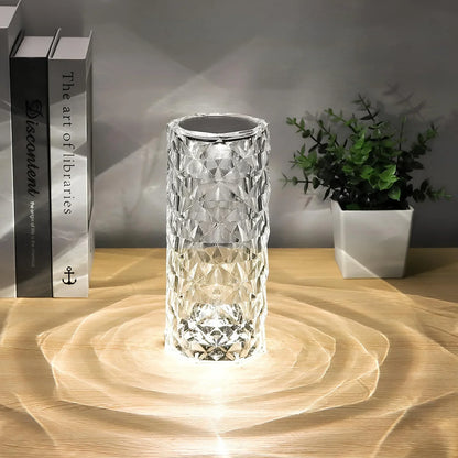 Clear faceted cylinder lamp beside books and plants