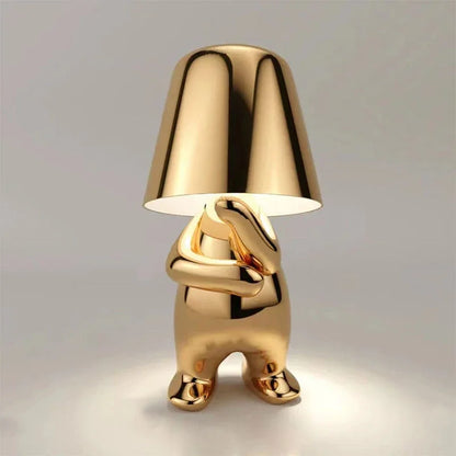 Modern Thoughtful gold rechargeable LED table lamp featuring a minimalist figure design with a polished metallic finish and touch control functionality.