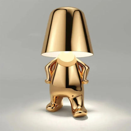 Gold rechargeable LED table lamp in a walking figure design with a minimalist metallic finish and touch control, perfect for a modern bedside.