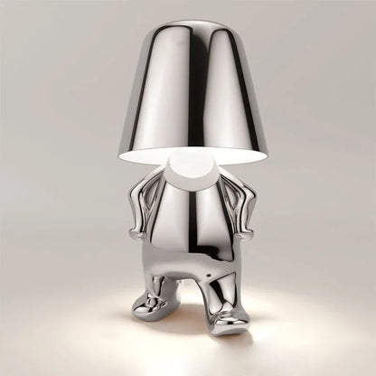 A modern silver rechargeable LED table lamp shaped like a walking figure with a polished metallic finish and a minimalist design for bedside or desk use.
