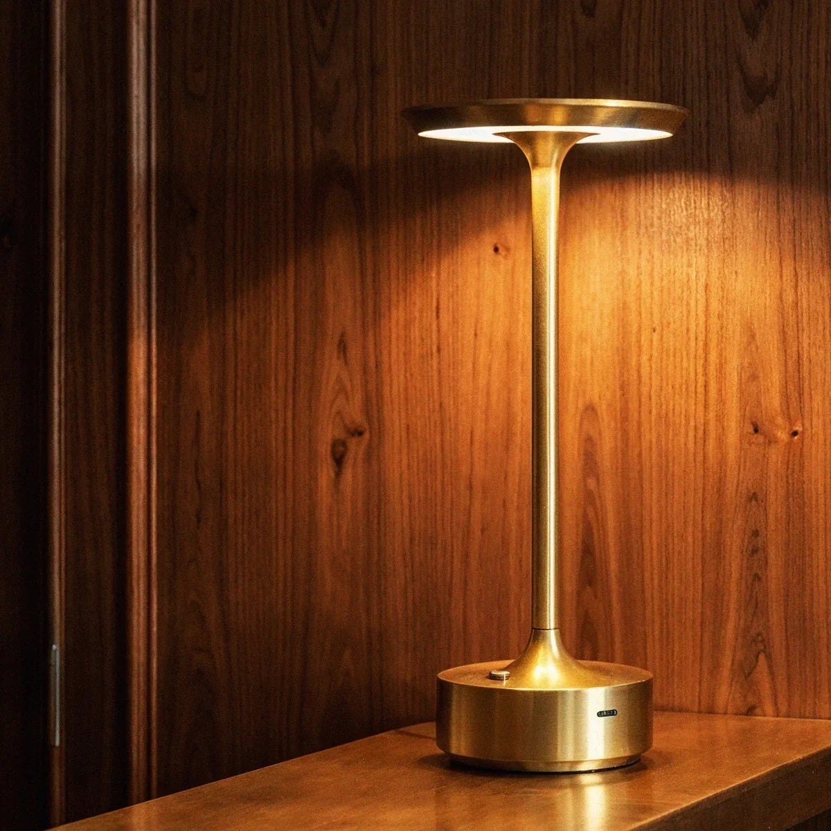 Gold table lamp casting warm light onto a wall