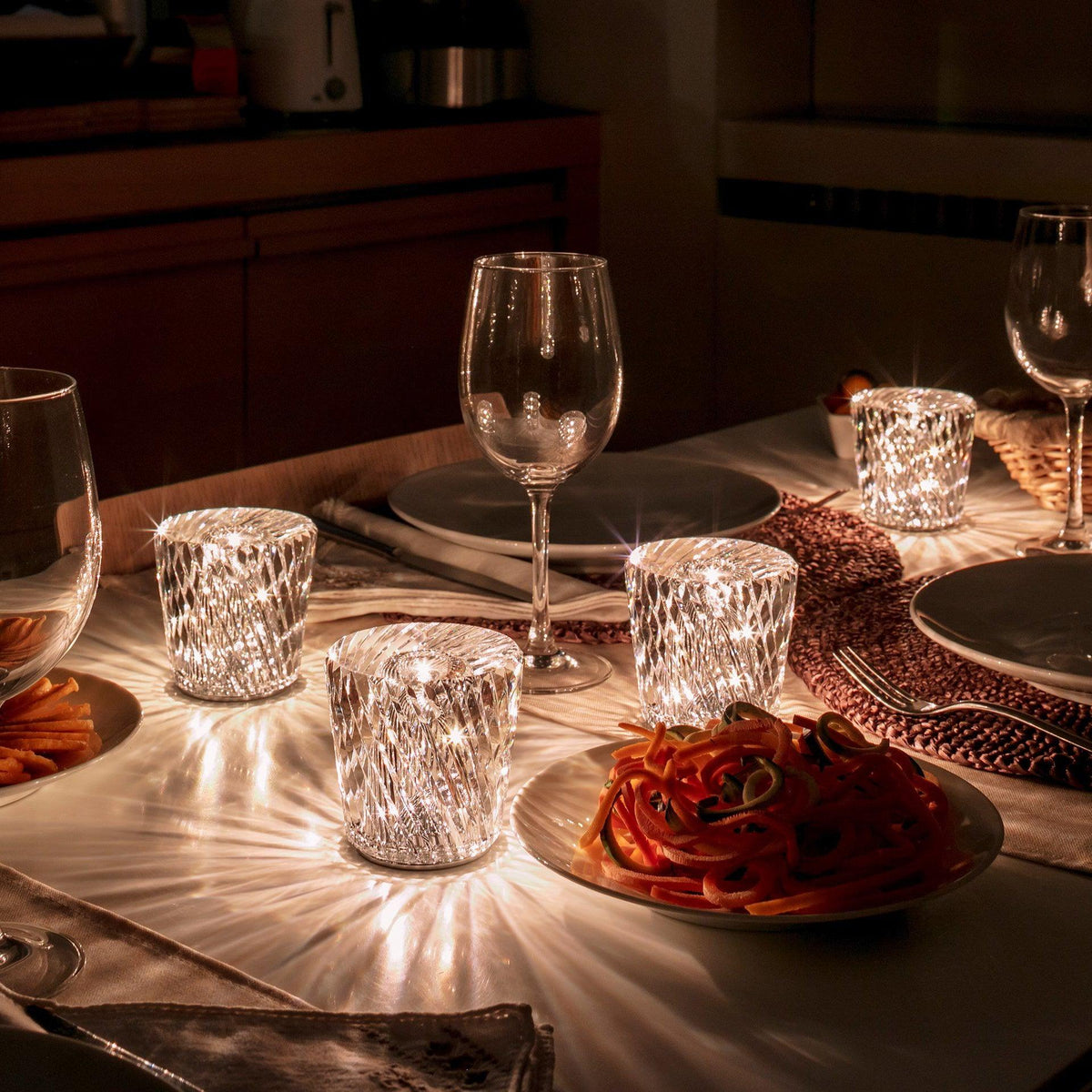 Mini crystal glass lamps casting light patterns on a dining table