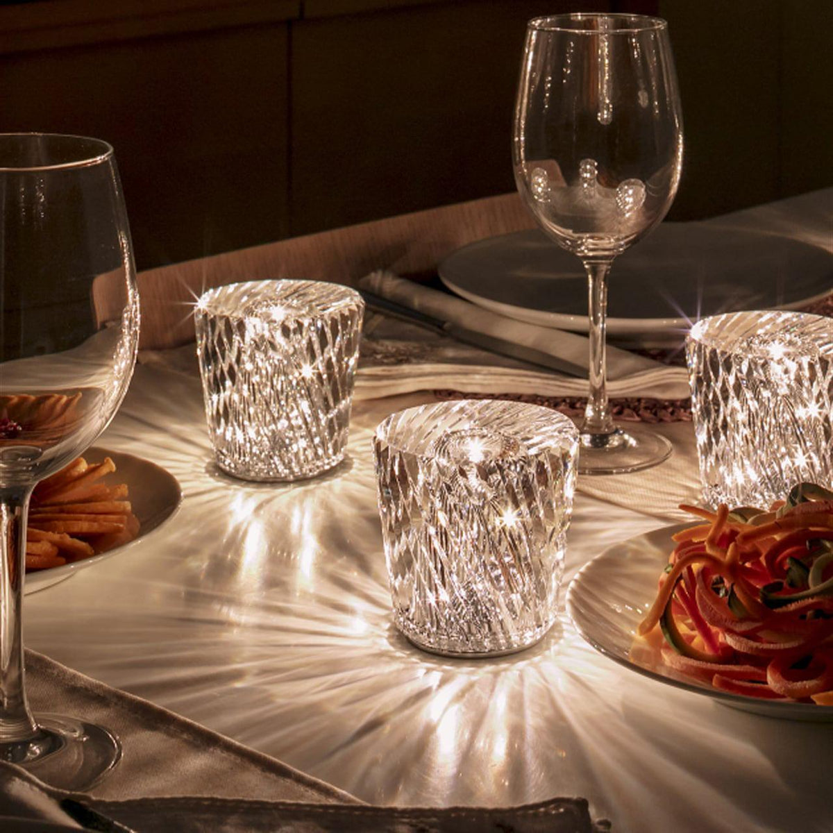Mini crystal glass lamps casting light patterns on a dining table