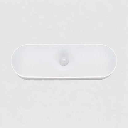 A sleek, white oval rechargeable LED wall light featuring a central motion sensor, designed for convenient indoor lighting in a minimalist style.