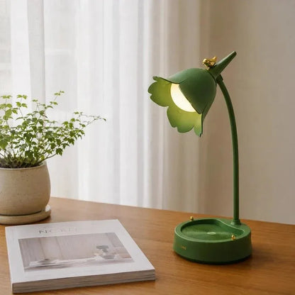 Green flower desk lamp beside an open book