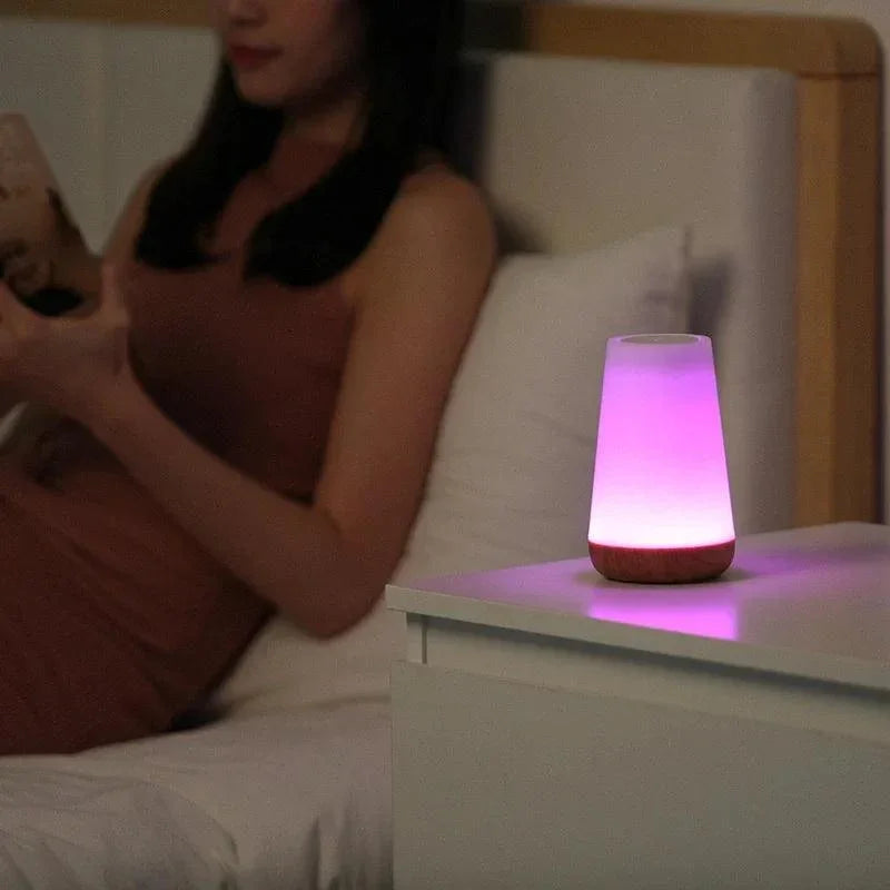 Purple night light beside a person relaxing in bed