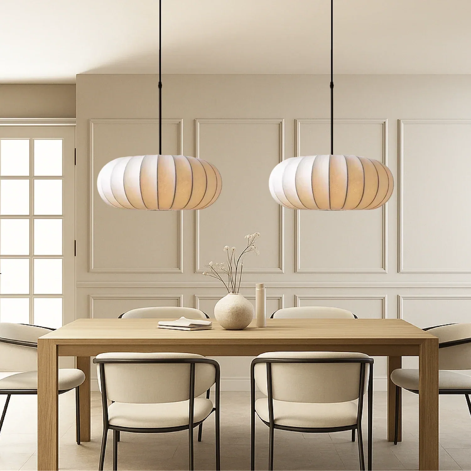 Two retro silk pumpkin pendant lights hanging above a wooden dining table with contemporary chairs in a neutral-toned dining room.