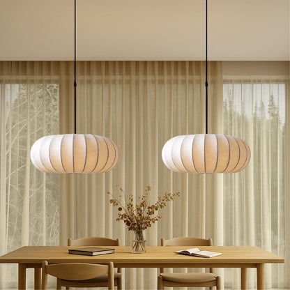 Two retro silk pumpkin pendant lights hanging above a wooden dining table with chairs in a contemporary dining room with neutral curtains.