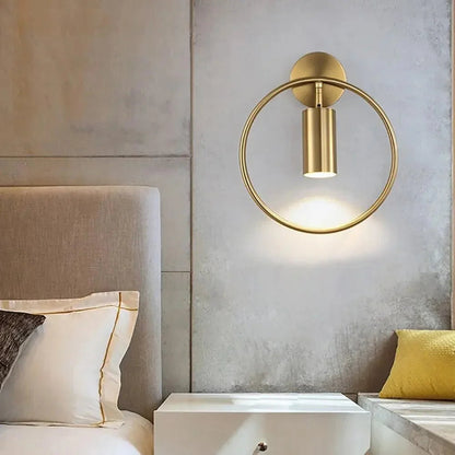 Gold ring wall light beside a bed