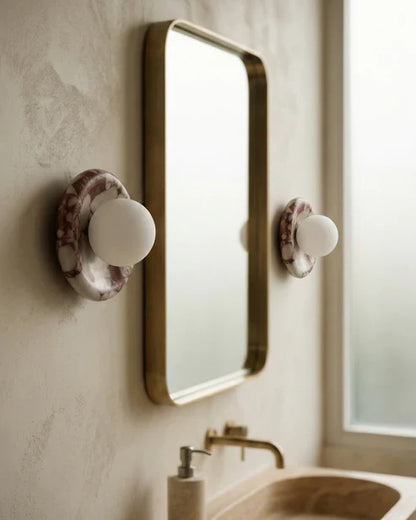 Marble globe wall lamps beside a mirror