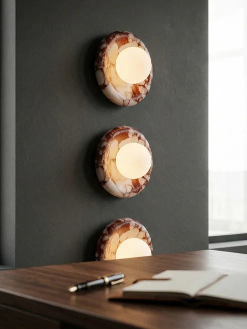 Illuminated red marble globe sconces above a desk