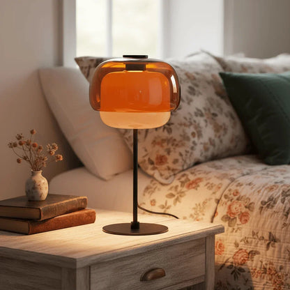 Orange glass lamp beside floral cushions