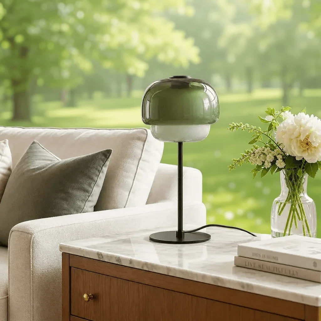 Grey green glass table lamp beside a window