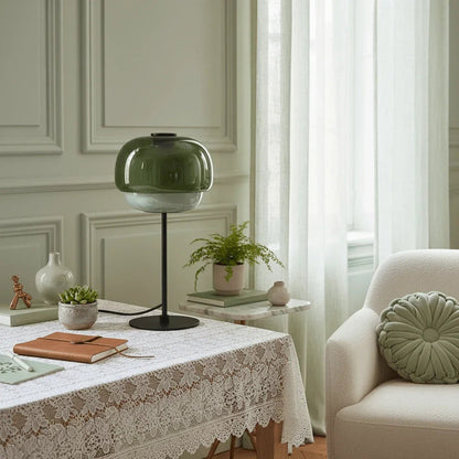 Grey green glass lamp on a lace-covered table