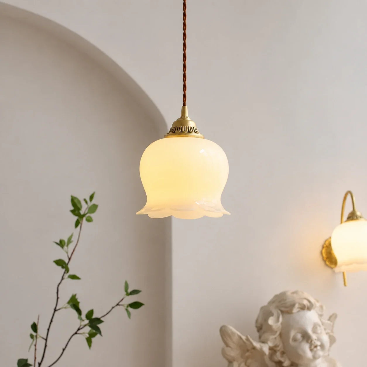 Scalloped floral pendant light with a glowing frosted glass shade and brass fixture, hanging elegantly in a vintage-inspired interior.
