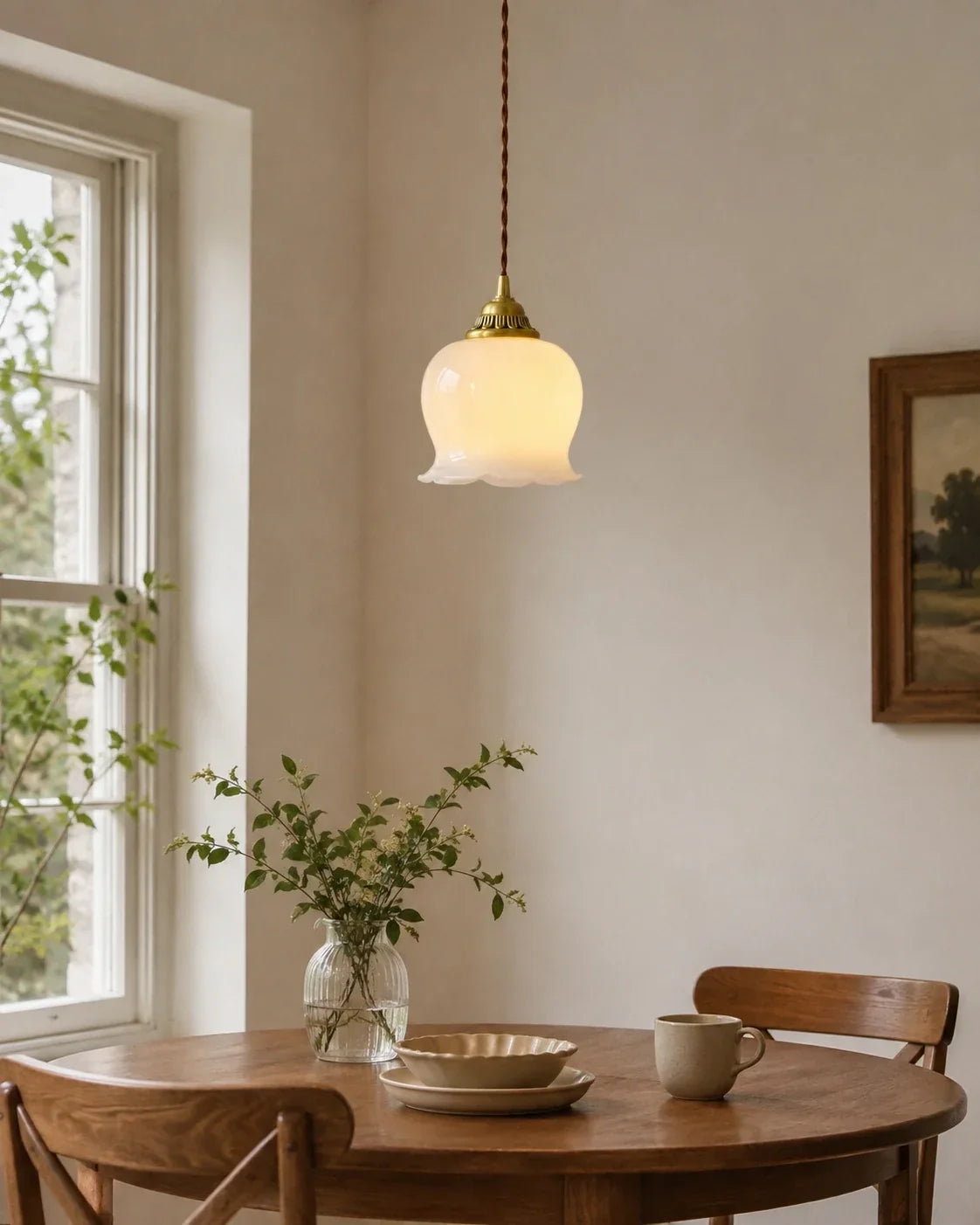 A vintage-style scalloped floral pendant light with a white glass shade and brass fixture, hanging above a wooden dining table.