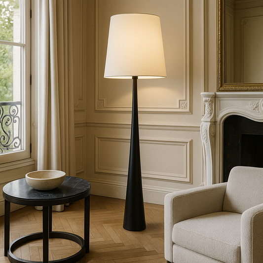 Scandinavian floor lamp with white shade and tapered black base beside an armchair
