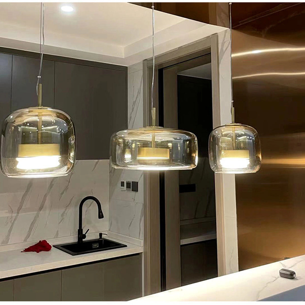 Three smoked grey glass dome pendant lights above a kitchen counter