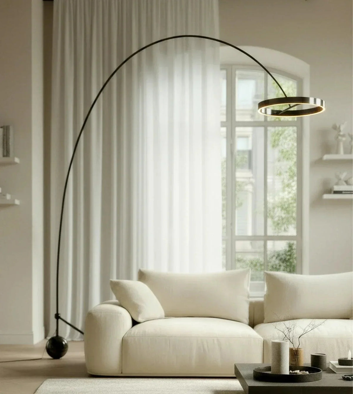 Black chrome arc floor lamp with ring-shaped head over a sofa
