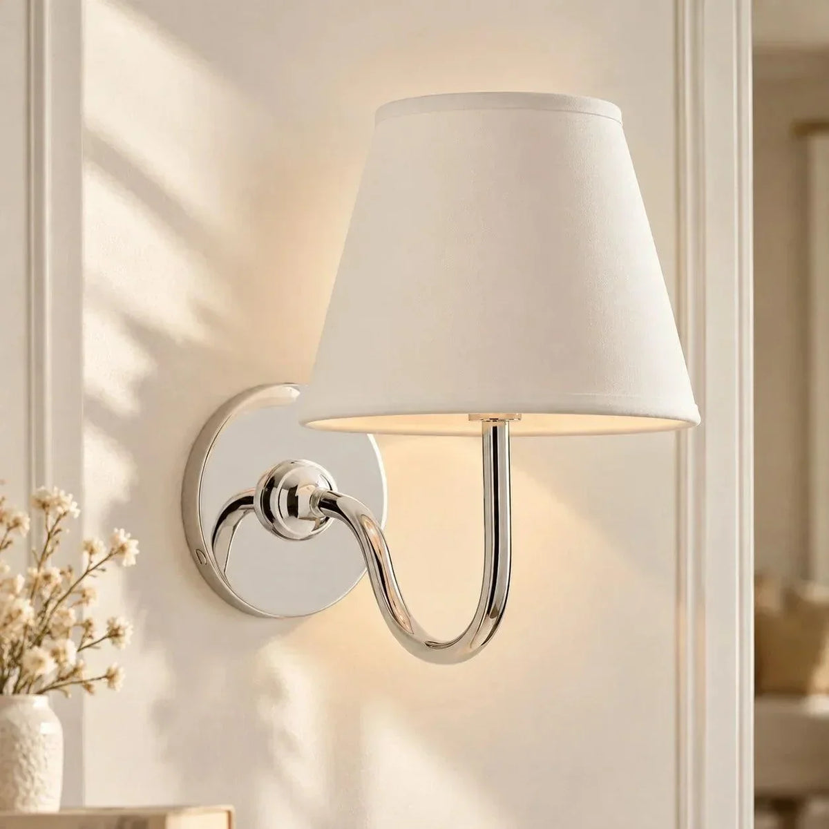 Chrome single-arm wall light with a plain shade