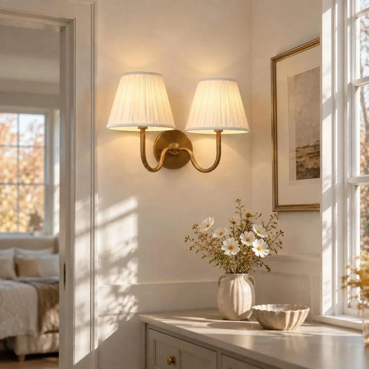 Double-arm brass wall light with pleated shades above a console