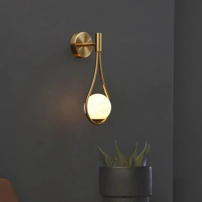 Gold teardrop wall light on a dark wall