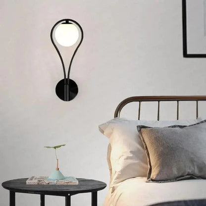Black teardrop globe light beside a bed