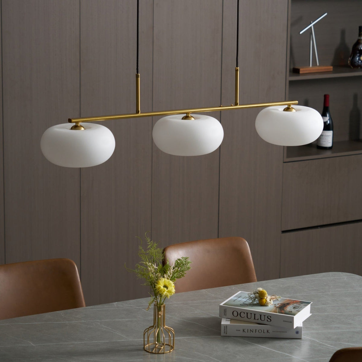 Gold-finish linear glass pendant above a dining table