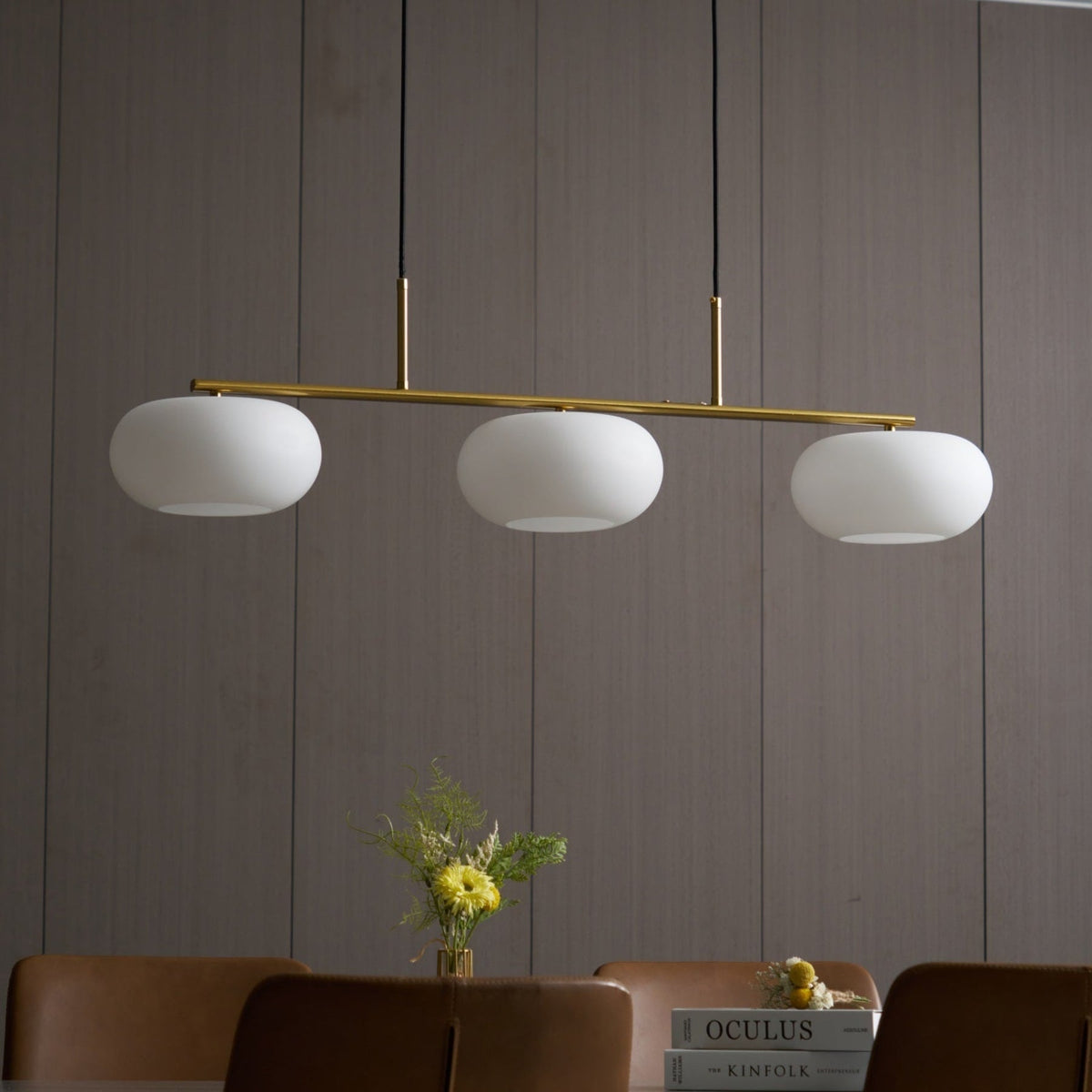 Gold-finish linear glass pendant above a dining table