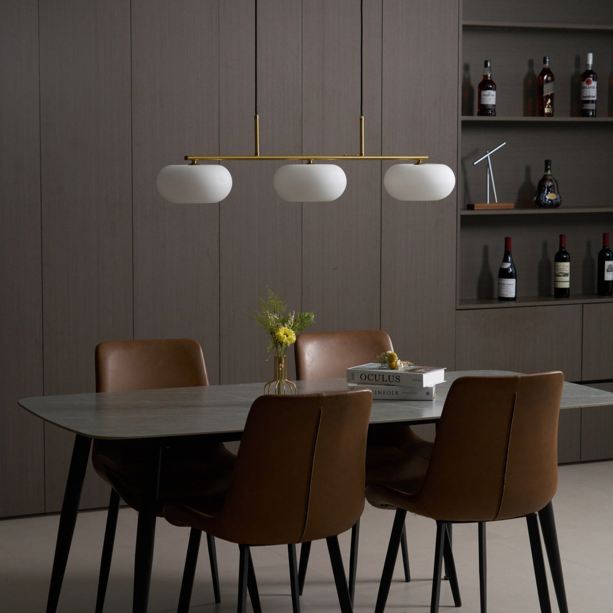Gold-finish linear glass pendant above a dining table