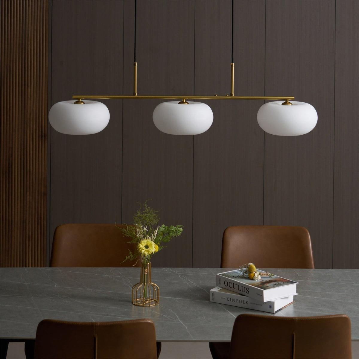 Gold-finish linear glass pendant above a dining table
