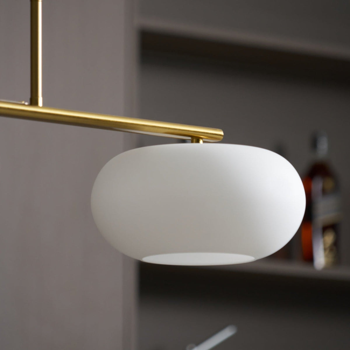 Close view of white glass shade and gold-finish pendant frame