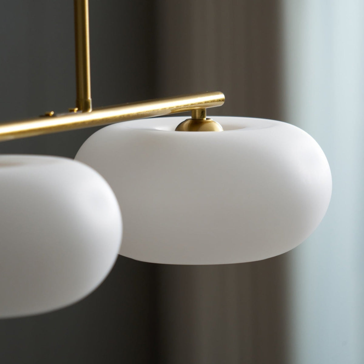 Close view of white glass shade and gold-finish pendant frame