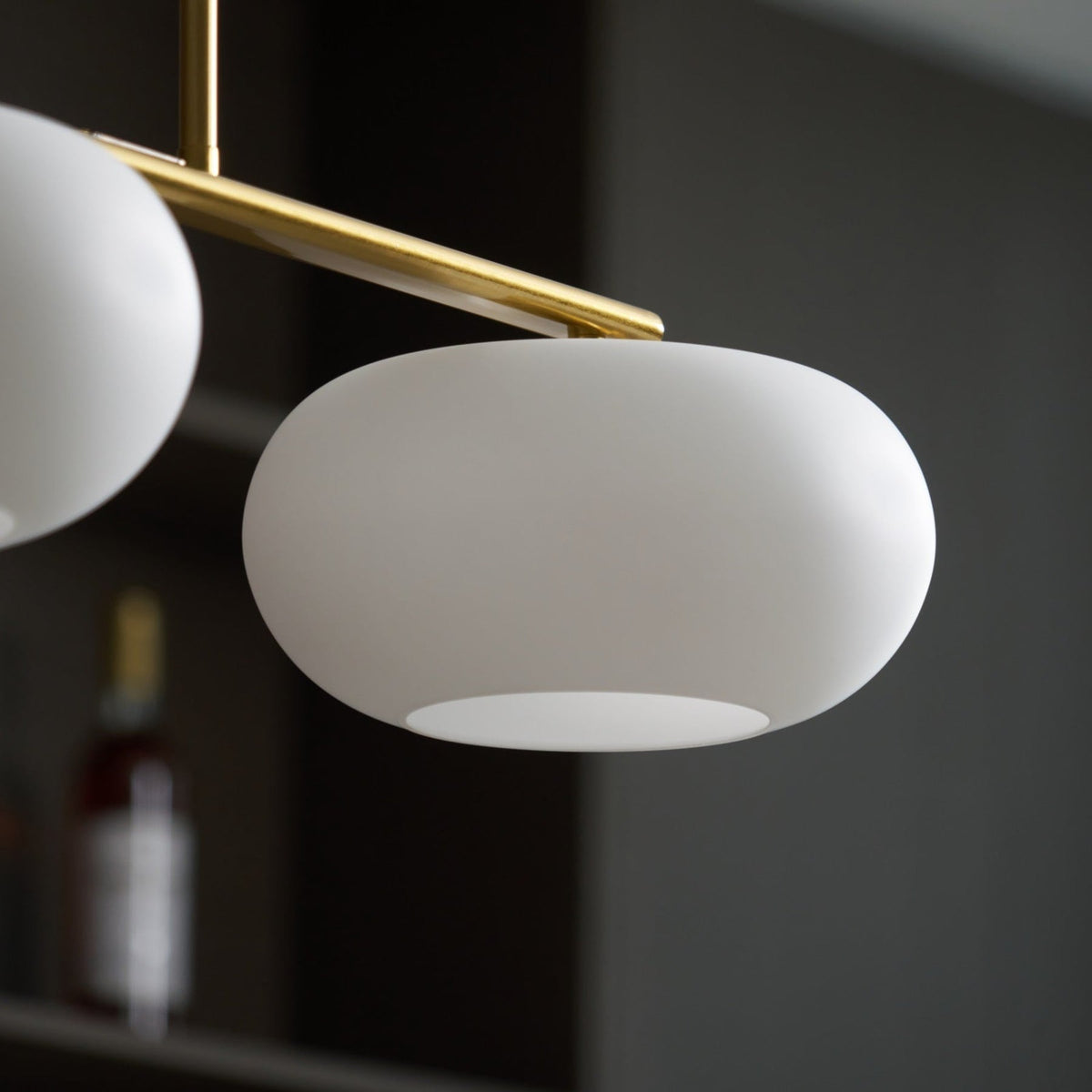 Close view of white glass shade and gold-finish pendant frame