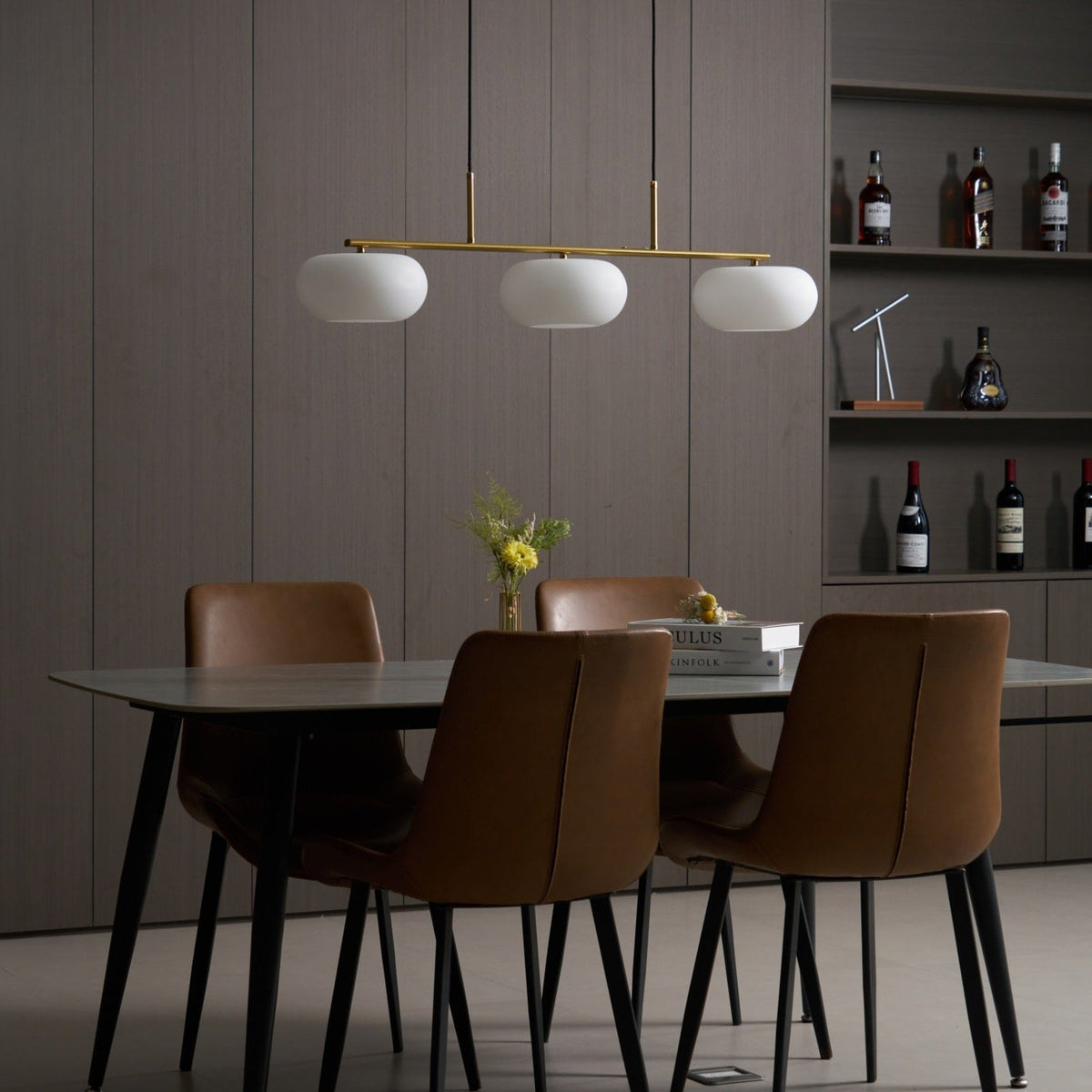 Gold-finish linear glass pendant above a dining table